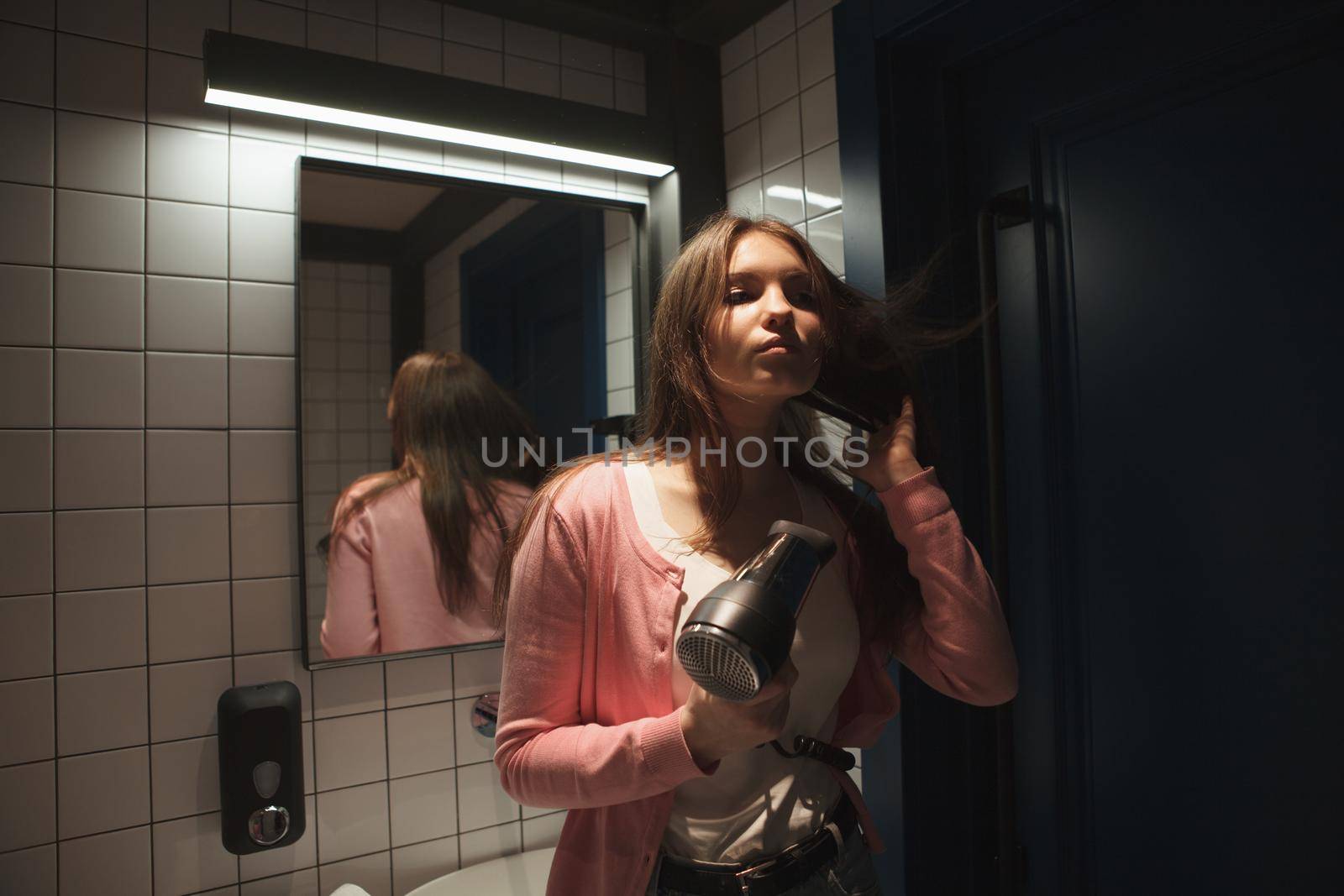 Woman blow drying her hair in the bathroom