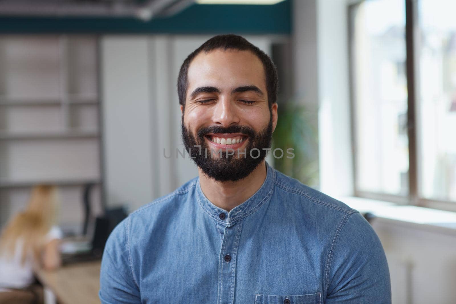 Close up of a handsome cheerful male entrepreneur smiling with his eyes closed