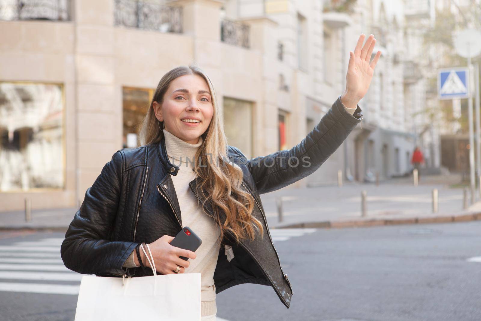 Beautiful woman waving, trying to catch taxi on city street