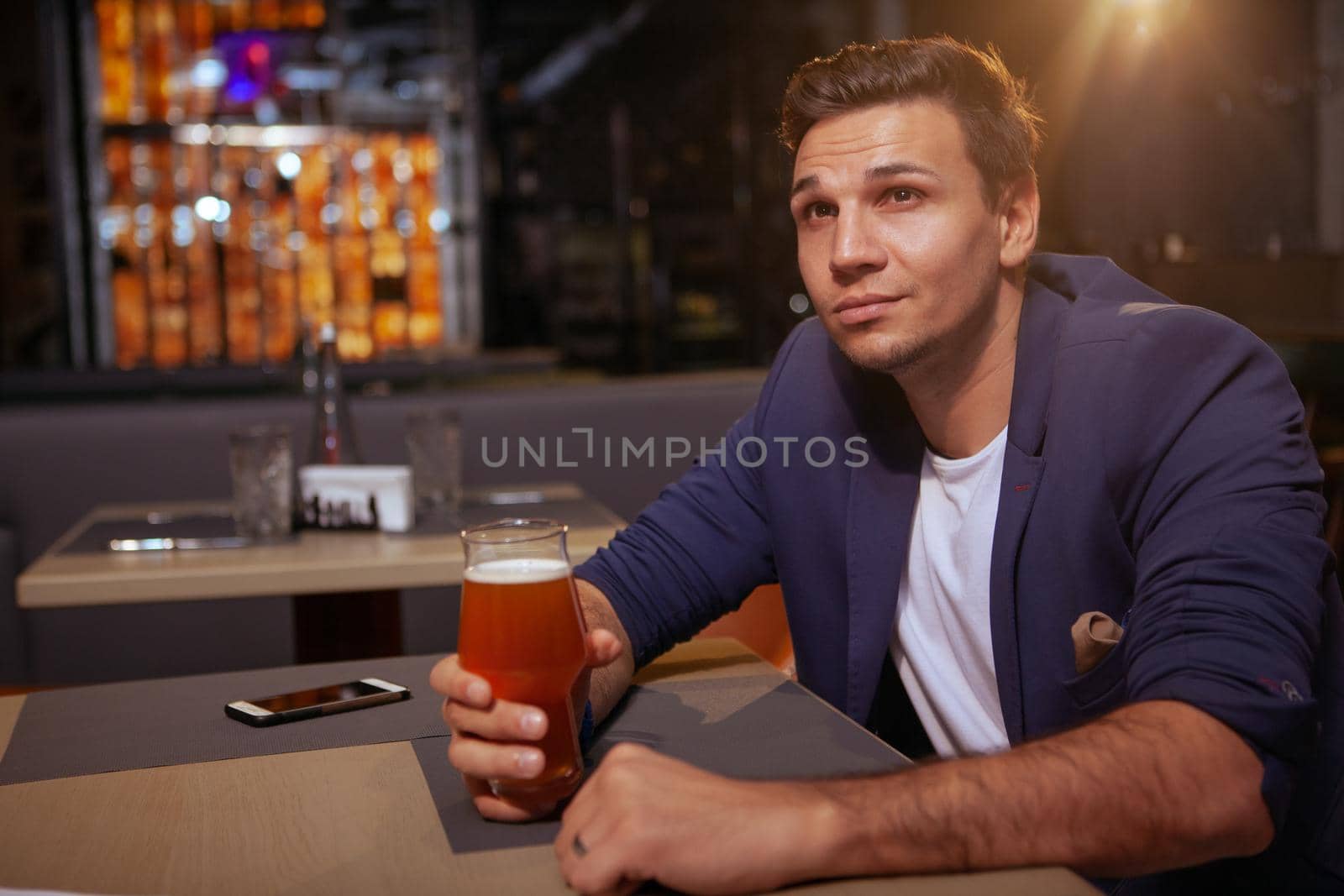 Handsome elegant young man enjoying glass of delicious beer at the pub, copy space