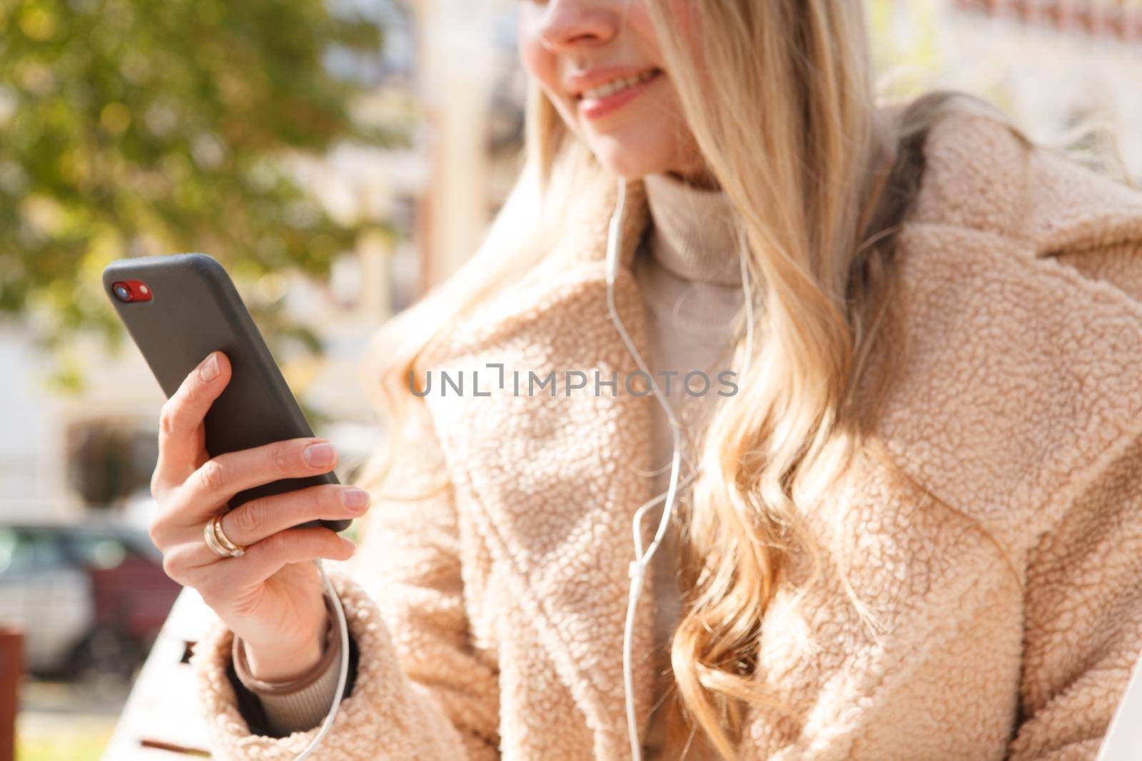 Cropped shot of a woman using smart phone with earphones outdoors