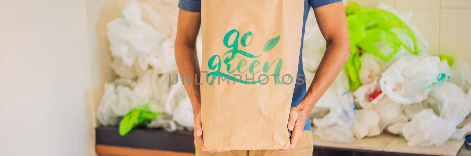 Man holding a package with the inscription GO GREEN amid a pile of plastic bags. Zero waste concept. The concept of World Environment Day BANNER, LONG FORMAT by galitskaya