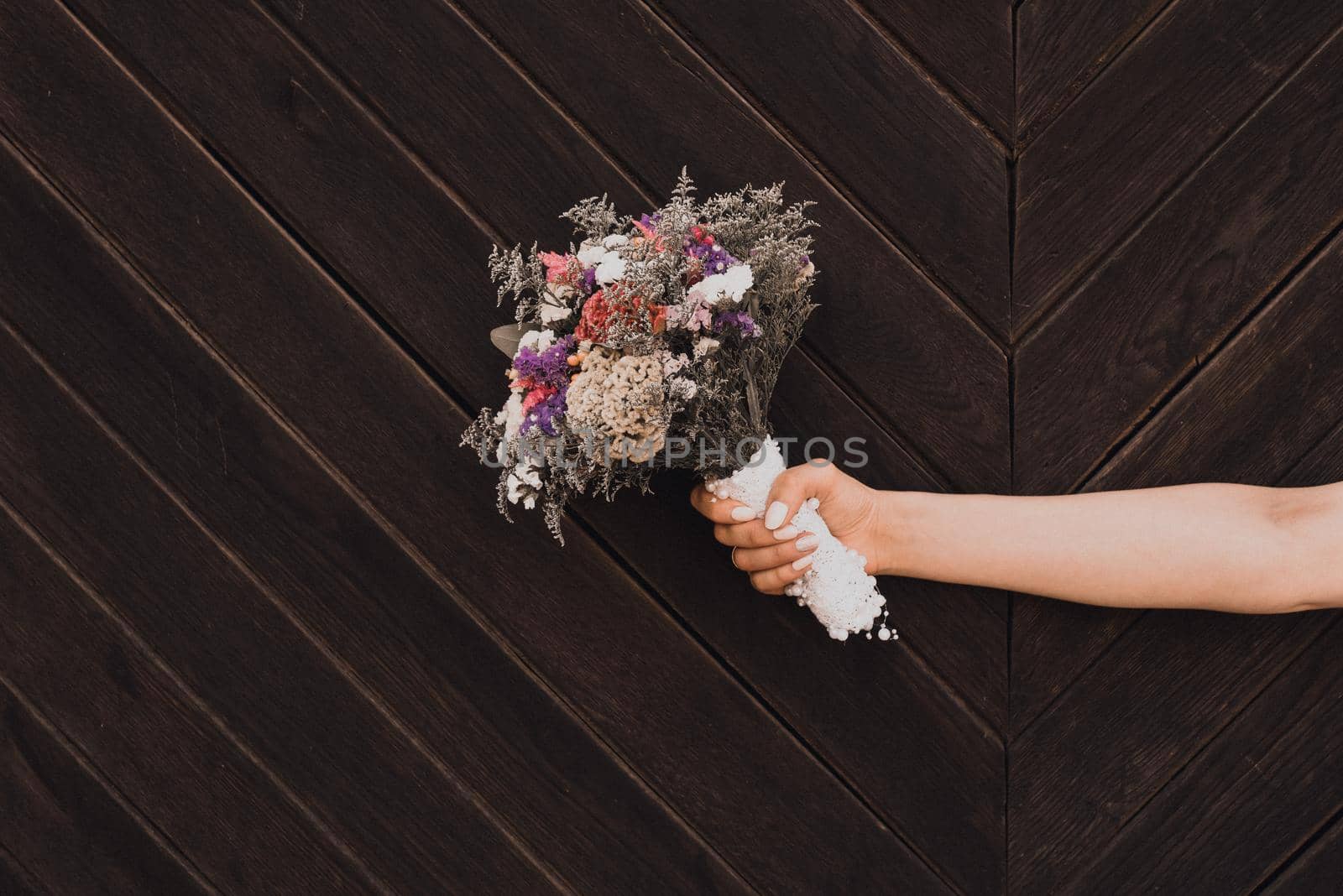 Wedding bouquet in bride's hands on wooden plank background