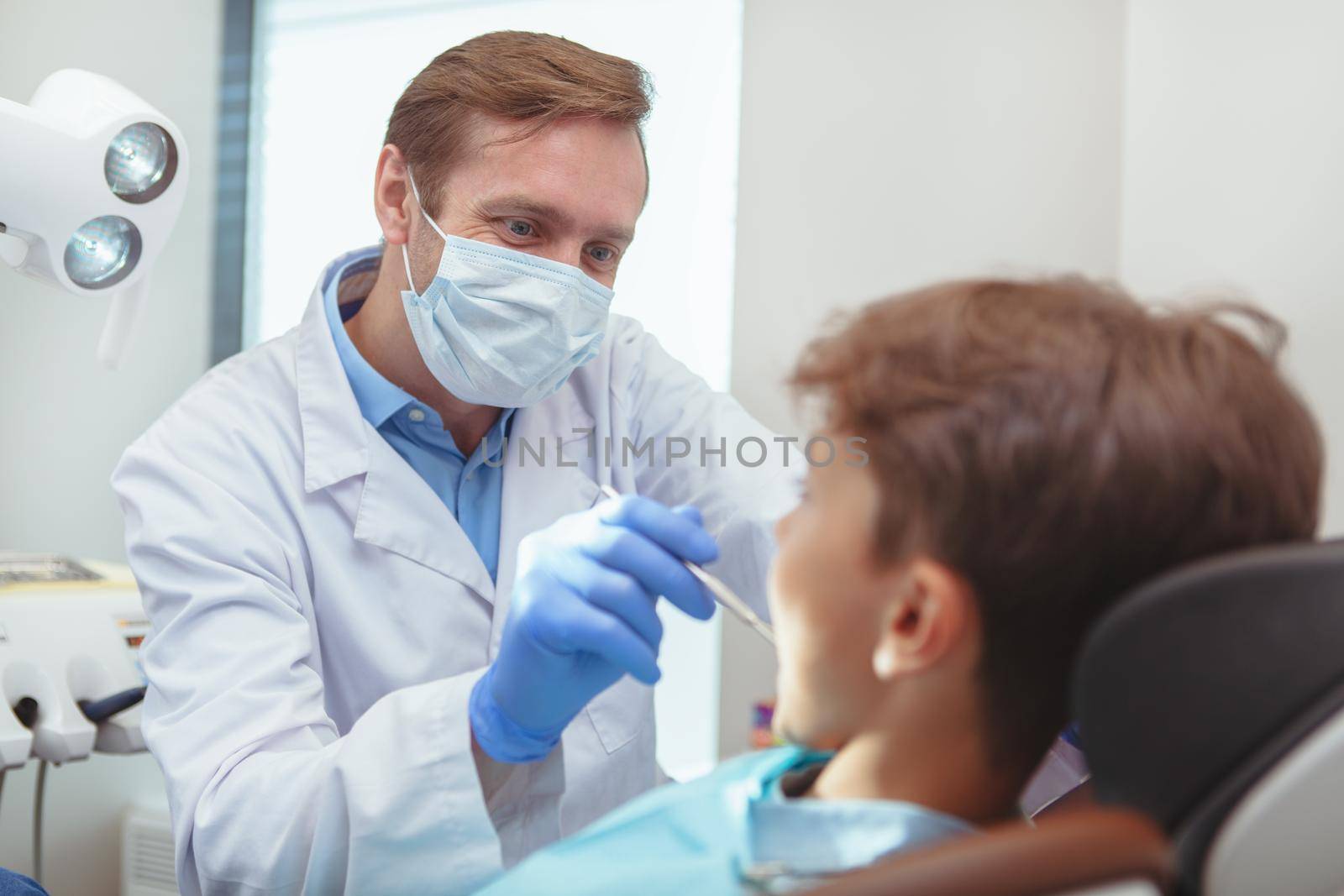 Charming young boy getting teeth checkup at the dentist by MAD_Production