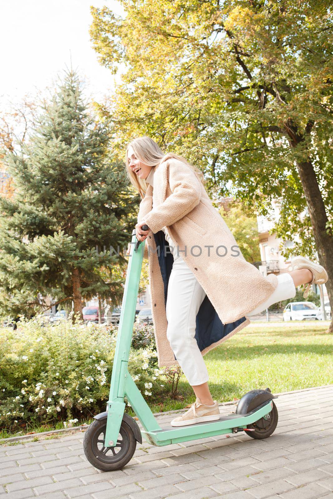 Full length shot of a happy woman enjoying riding electric scooter in the park