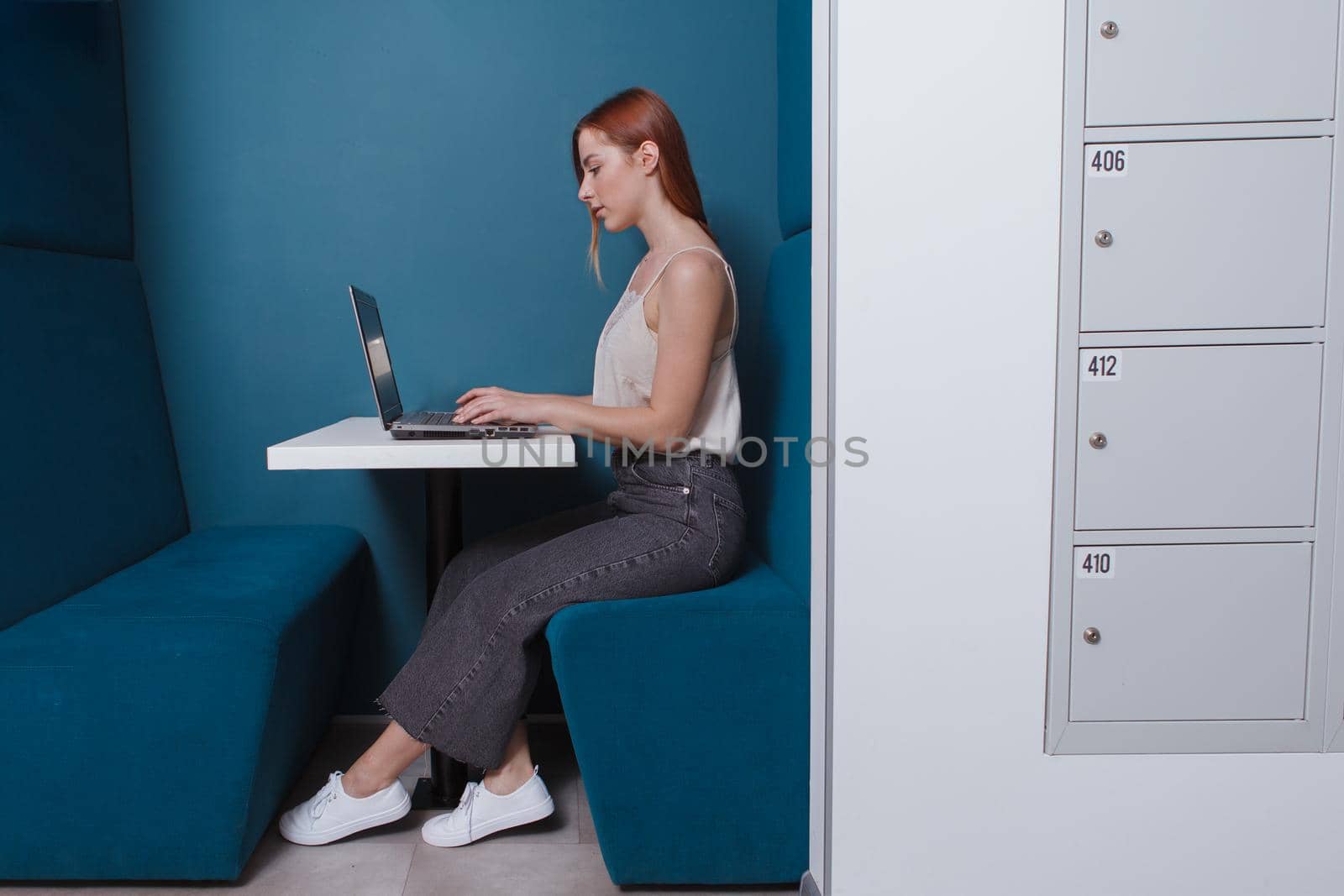 Young woman working on her laptop in a modern co-working office, copy space