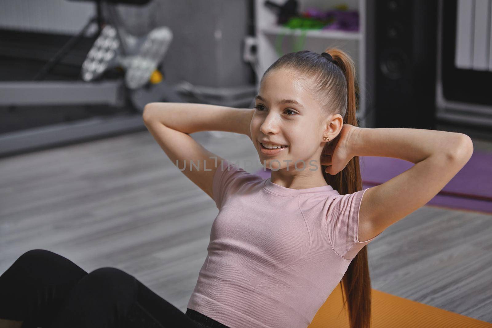 Cheerful teenage girl doing situps at the gym