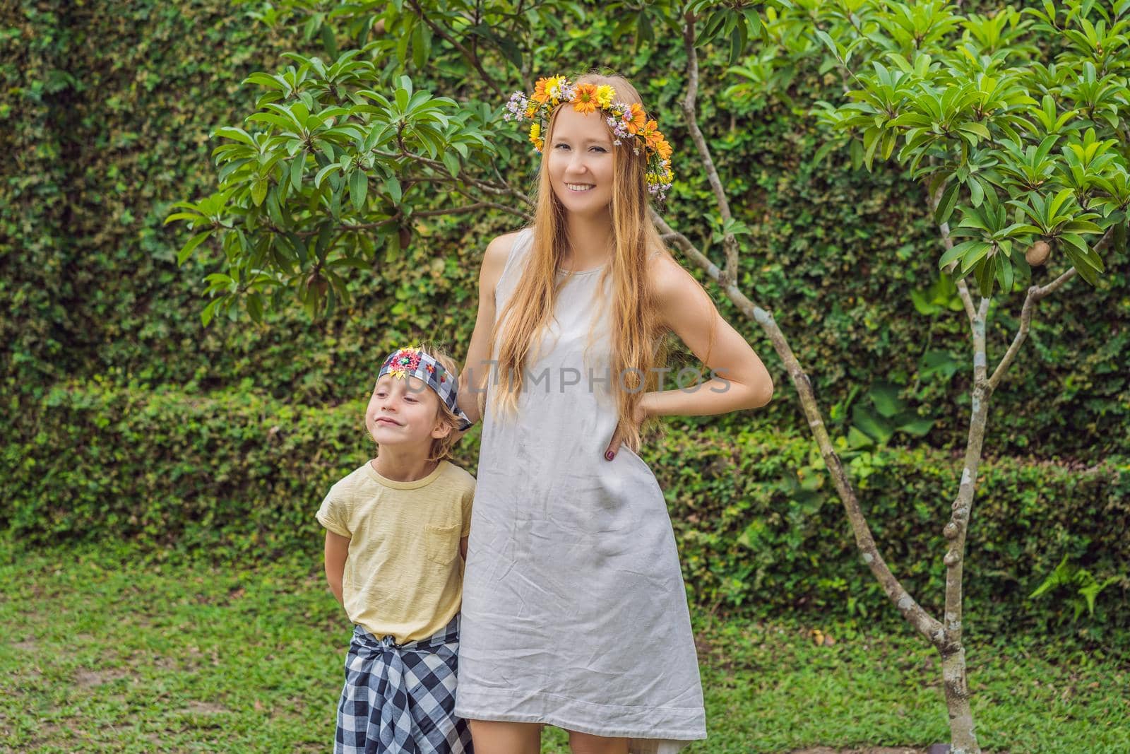 Boy tourist in sarong, national Balinese clothing and his mother with a wreath on his head by galitskaya