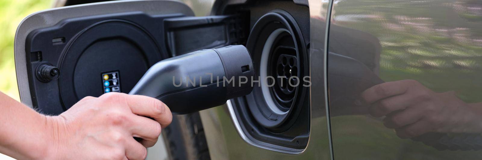 Man holding a pipe for refueling an electric car by kuprevich
