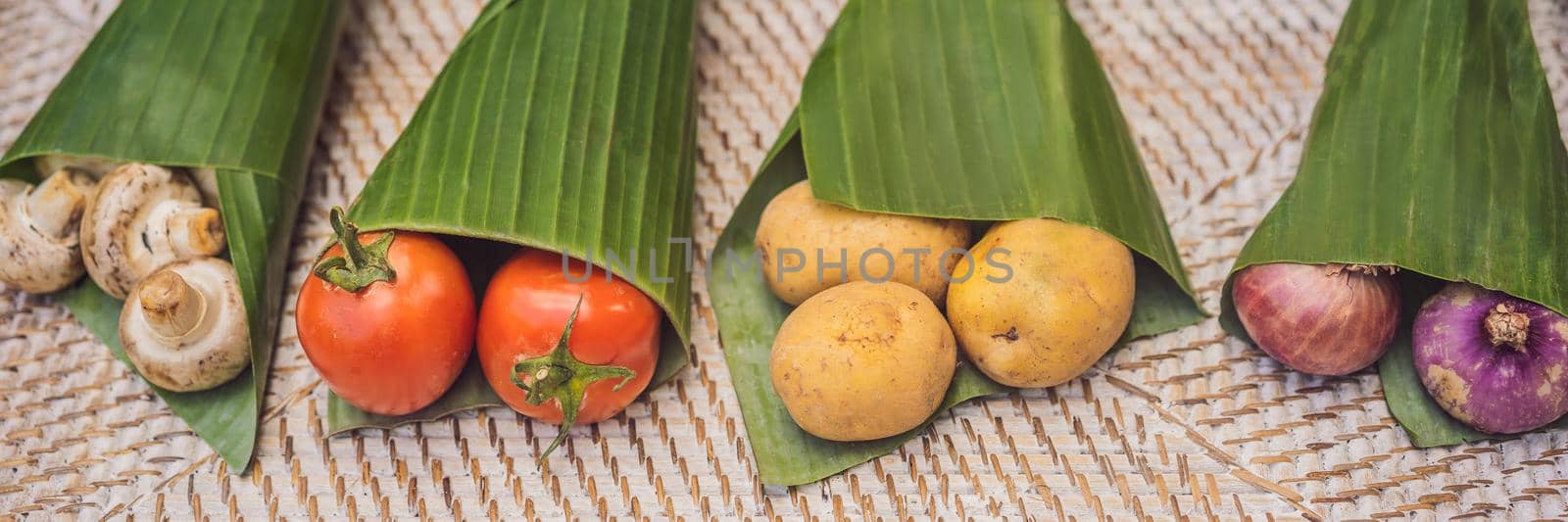 BANNER, LONG FORMAT Eco-friendly product packaging concept. Vegetables wrapped in a banana leaf, as an alternative to a plastic bag. Zero waste concept. Alternative packaging by galitskaya