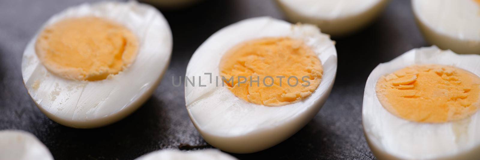 Boiled chicken eggs cut in half on dark background by kuprevich