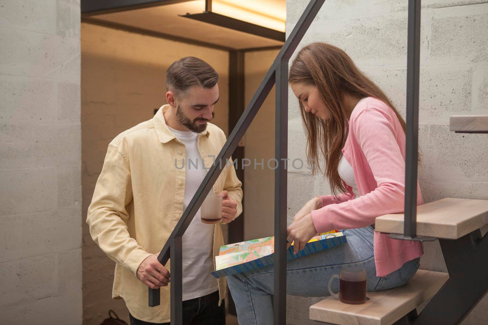 Couple looking at city map at their hostel room, preparing to go sightseeing