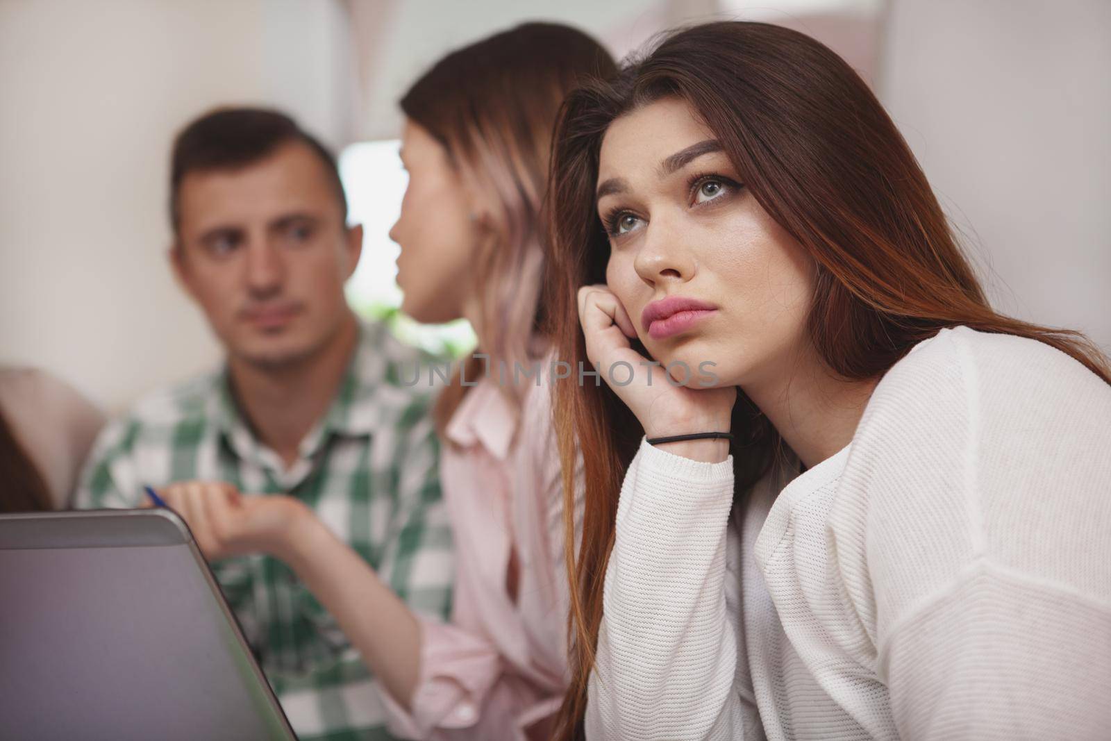 Overworking, boredom concept. Close up of a beautiful female college student looking bored during class. Attractive young woman student looking tired of studying