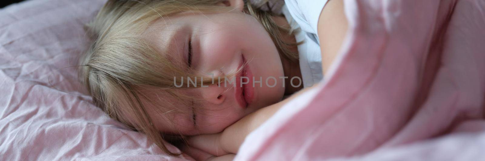 Little cute girl sleeping peacefully on the bed, close-up. Calm atmosphere for a child, carefree childhood, tranquility