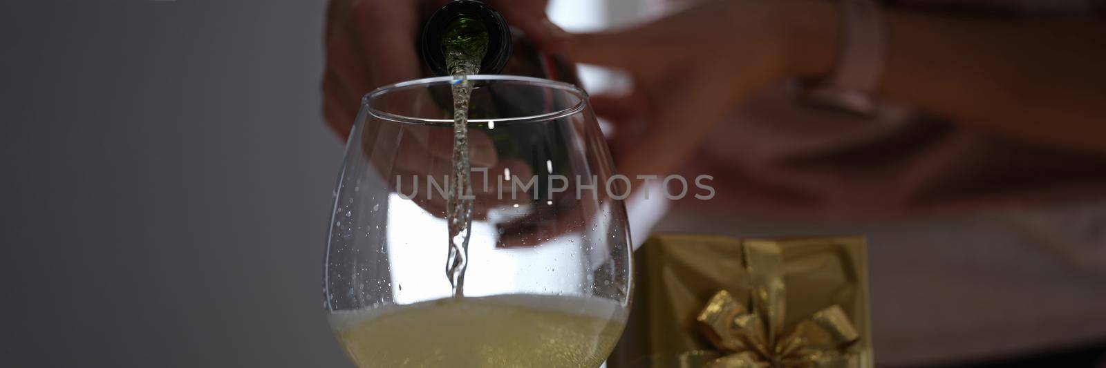 A woman pours champagne from a bottle into a glass, celebration. Family holiday event, wedding anniversary, surprise