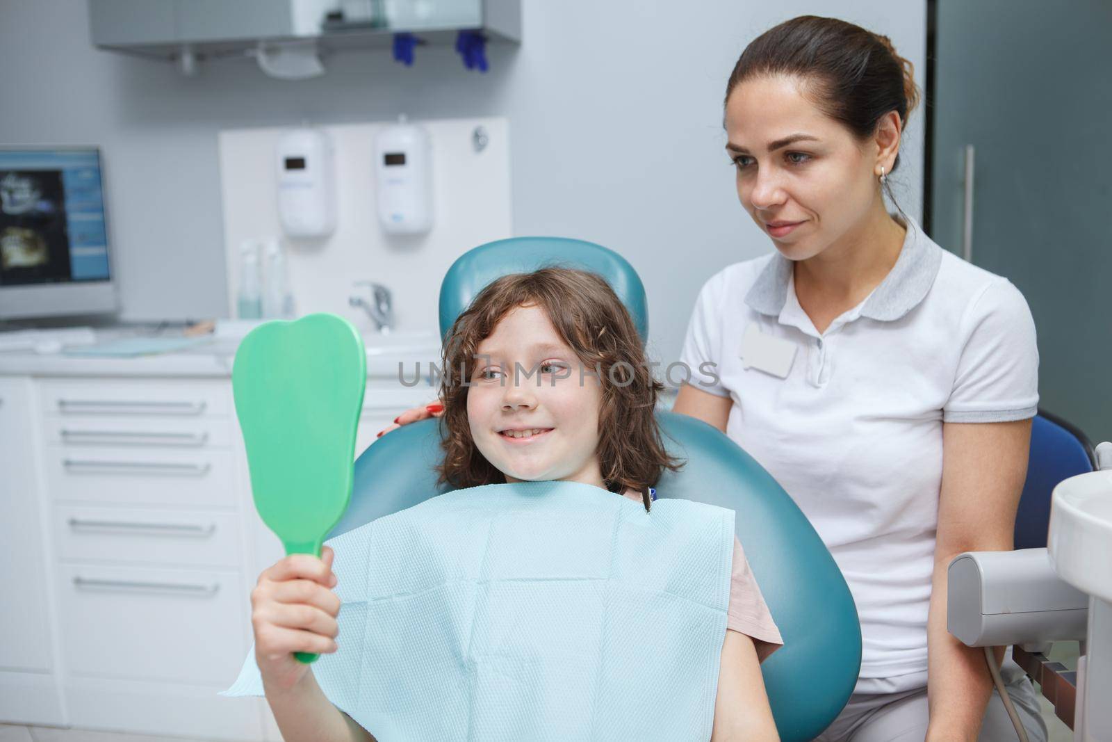 Young female dentist working with child patient at her clinic