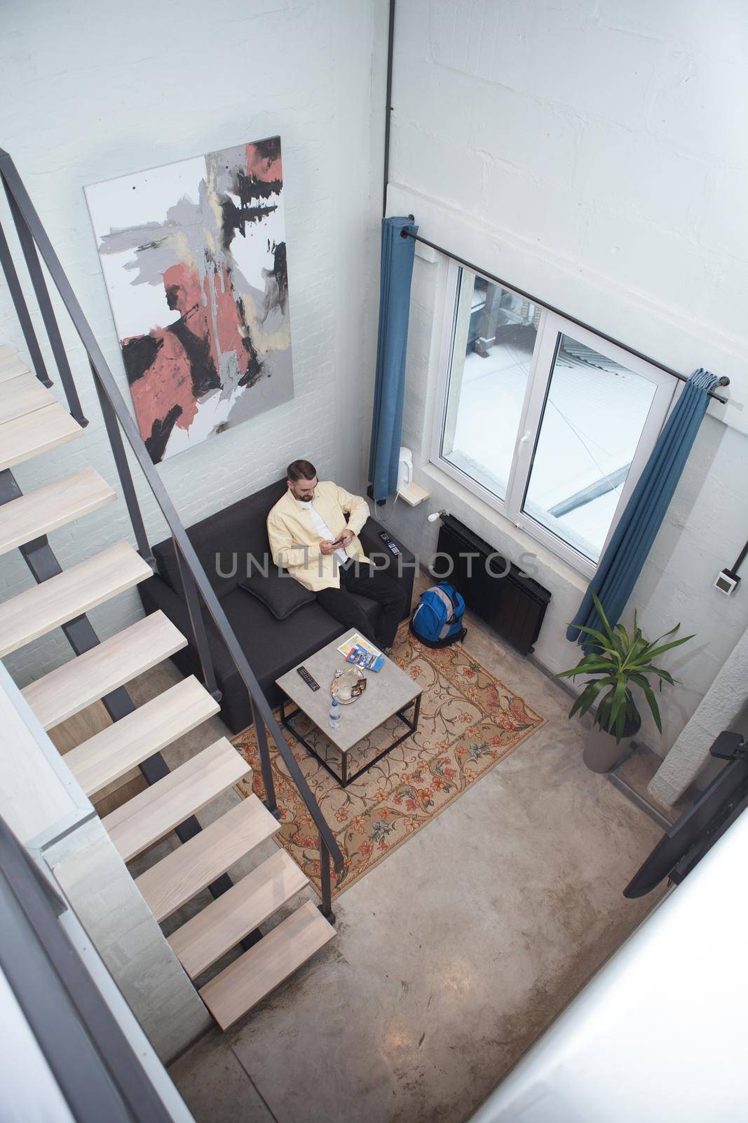 Vertical top view shot of a man resting on a couch at his hostel room