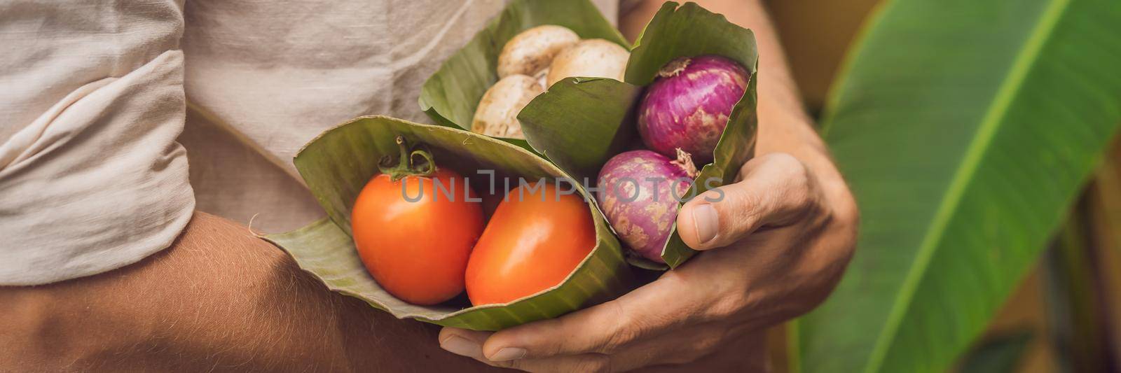 BANNER, LONG FORMAT Eco-friendly product packaging concept. Vegetables wrapped in a banana leaf, as an alternative to a plastic bag. Zero waste concept. Alternative packaging.