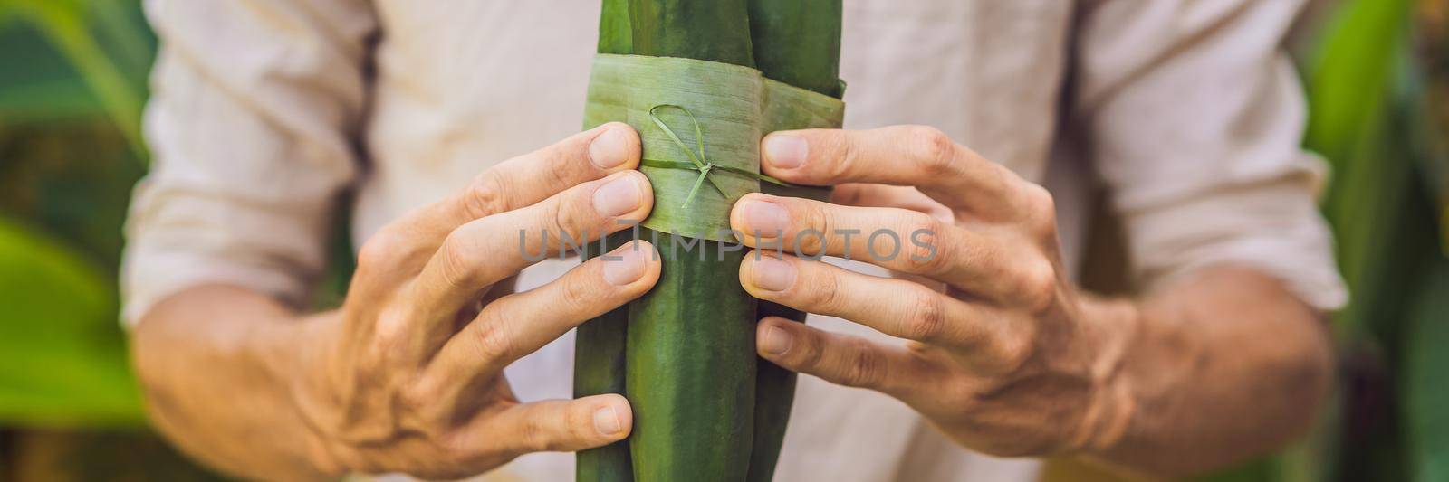 BANNER, LONG FORMAT Eco-friendly product packaging concept. Cucumber wrapped in a banana leaf, as an alternative to a plastic bag. Zero waste concept. Alternative packaging by galitskaya