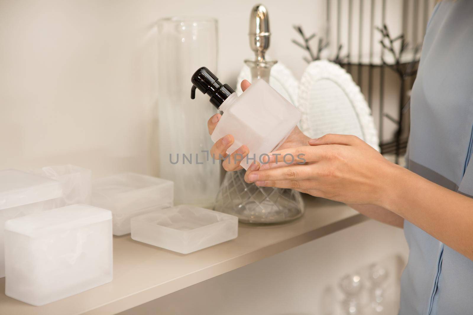 Cropped close up of a woman holding soap dispenser examining it while shopping at houseware store for bathroom accessories copyspace home consumerism purchase decor interior coziness buy
