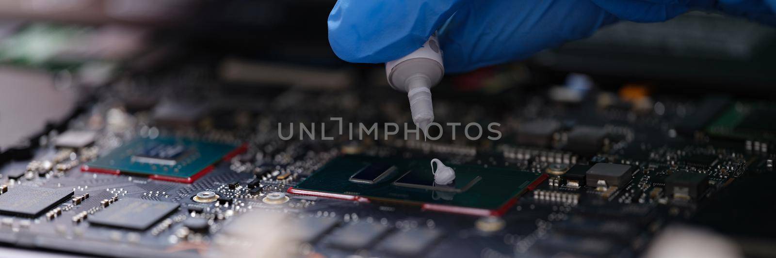 Thermal paste for the processor, computer repair, hands close-up. Workshop for servicing electronic devices, part of a laptop