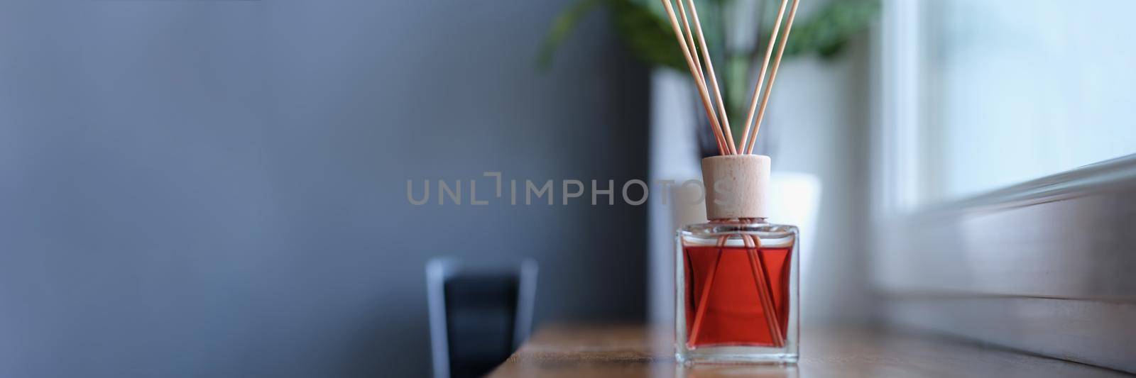 Diffuser with wooden sticks on the windowsill. Aromatherapy for an apartment, pleasant scent of perfume. Aroma bottle with essential oil