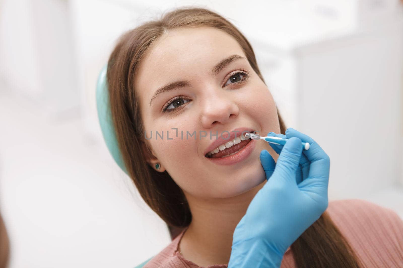 Close up of a beautiful woman getting dental treatment by dentist, using interdental toothbrush