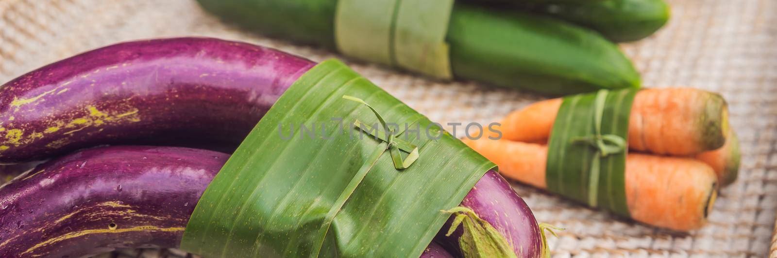 BANNER, LONG FORMAT Eco-friendly product packaging concept. Vegetables wrapped in a banana leaf, as an alternative to a plastic bag. Zero waste concept. Alternative packaging.