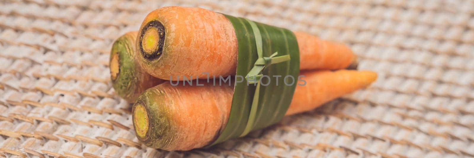 BANNER, LONG FORMAT Eco-friendly product packaging concept. Carrot wrapped in a banana leaf, as an alternative to a plastic bag. Zero waste concept. Alternative packaging by galitskaya