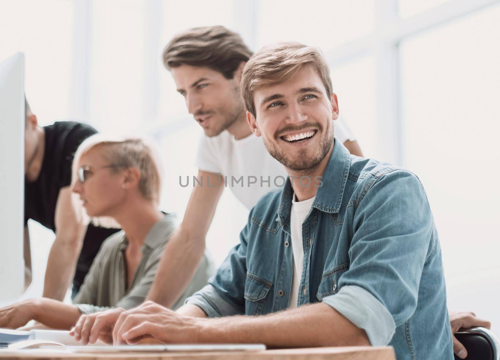 close up. smiling young man sitting at office Desk. photo copy space