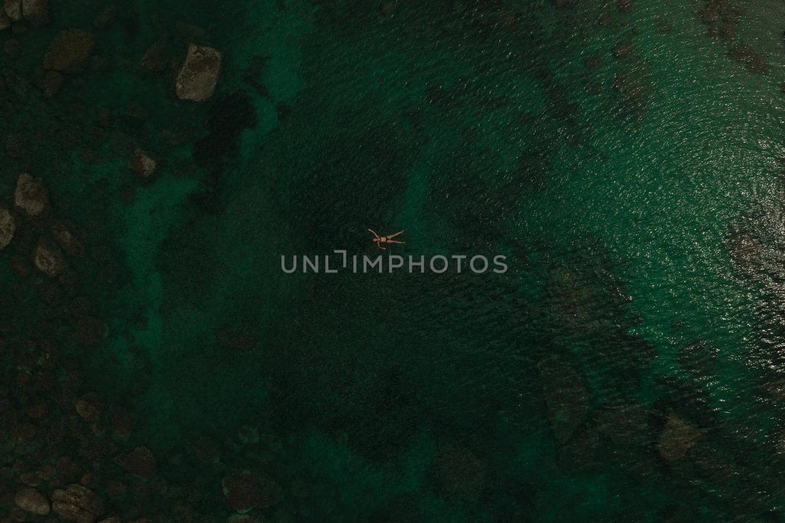 Aerial top nature view above green turquoise Adriatic sea in Albania. young woman swimming alone by AndriiDrachuk