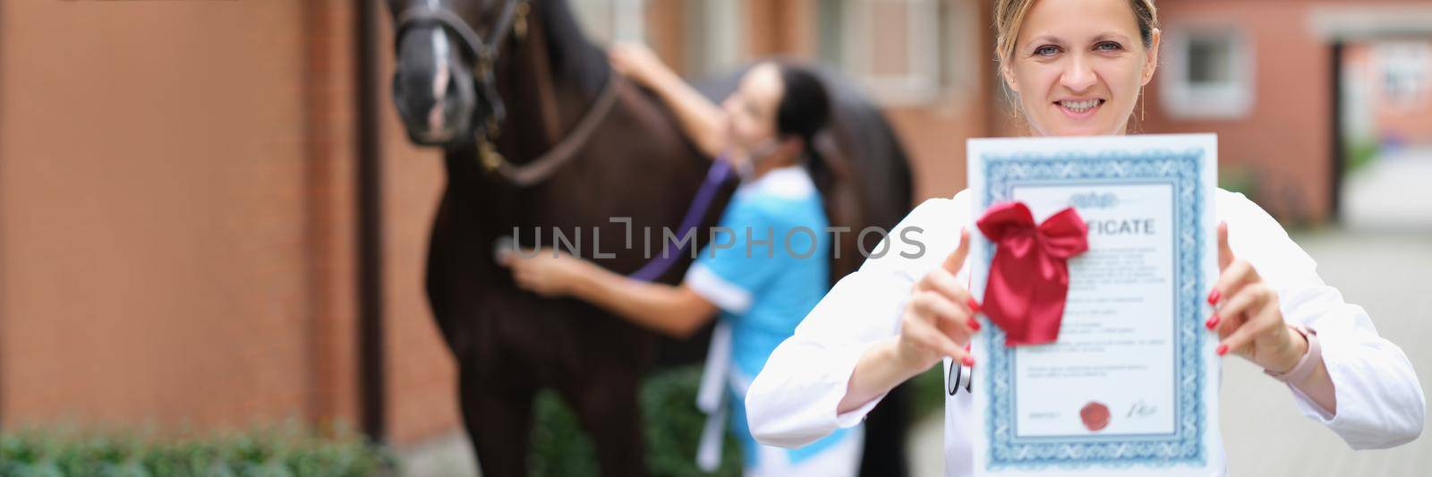 Woman veterinarian showing horse health certificate by kuprevich