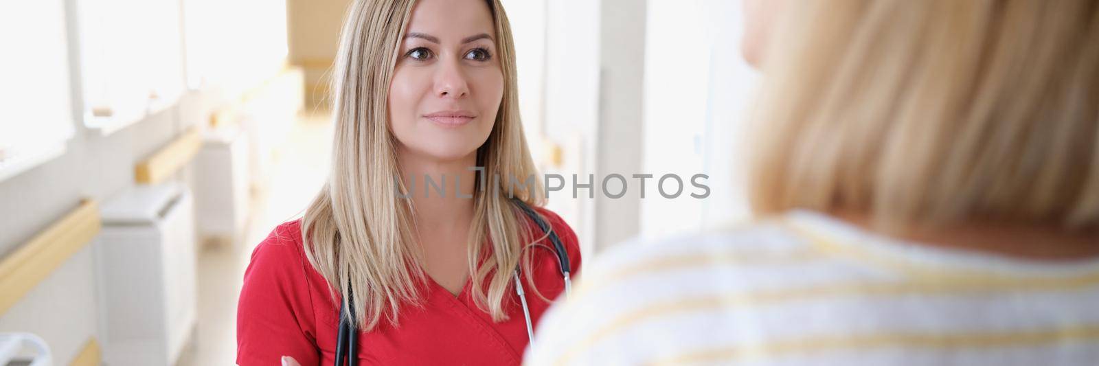 A female medical specialist speaks with a patient in the hallway. Meeting of the doctor with a relative of the patient