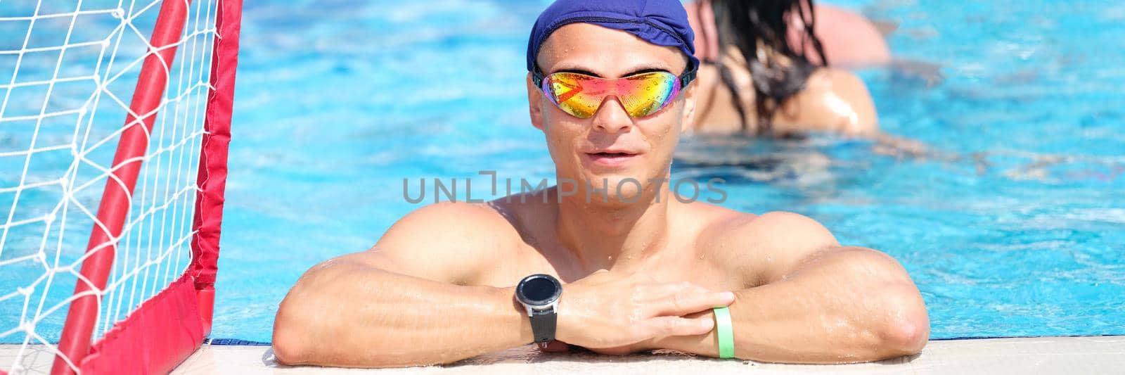 Young strong man in the pool, water polo player, close-up. Summer sports entertainment for tourists, relaxation