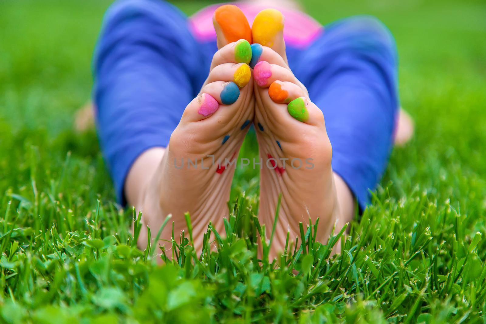 Feet of a child on the grass with a painted smile. Selection focus. Kid.