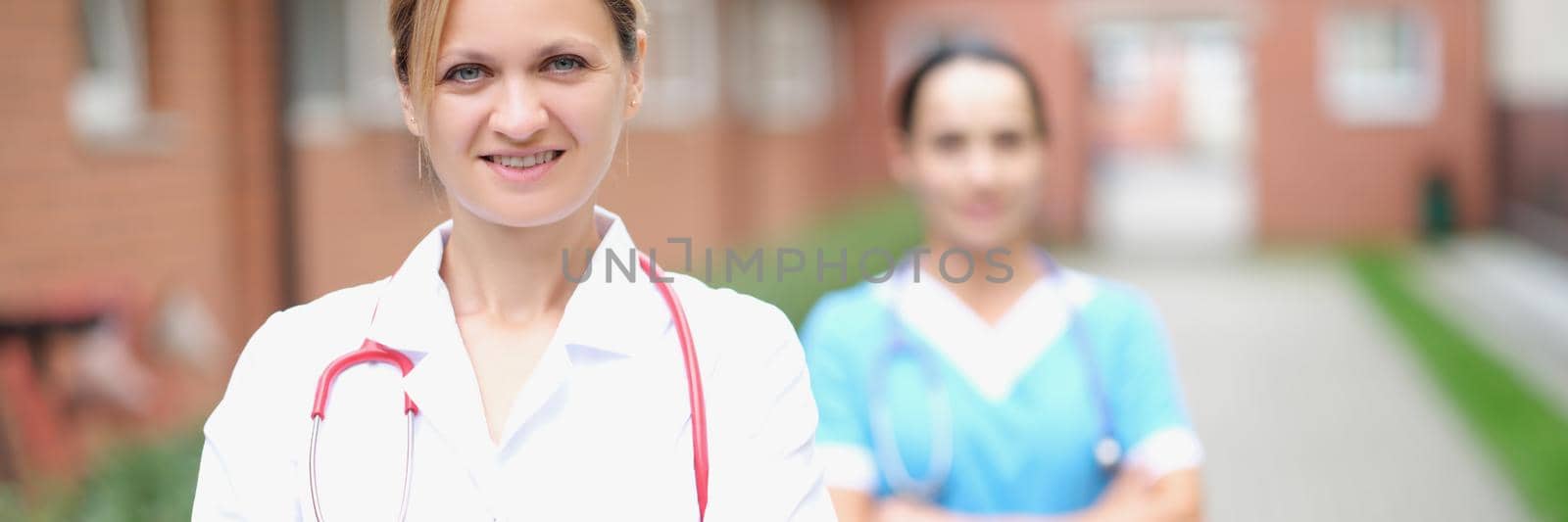 A woman doctor and a nurse are standing on the street near the clinic, close-up. Professional staff of the vetirina clinic