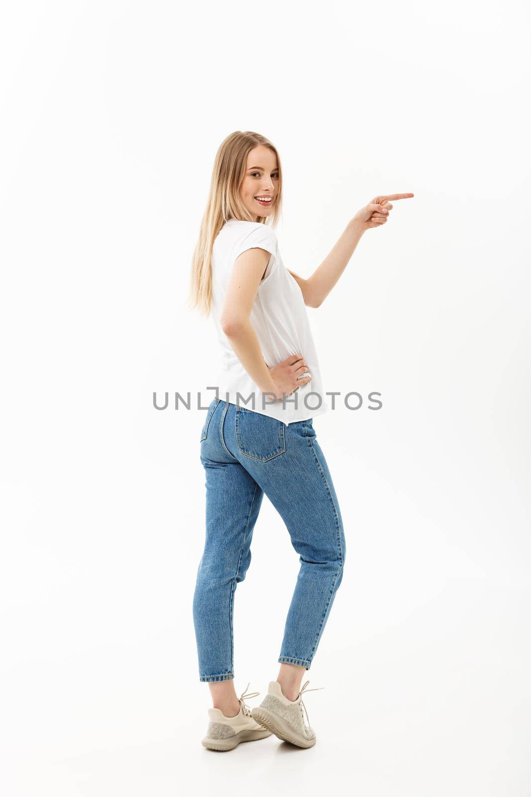 Lifestyle Concept: Portrait woman pointing or pushing something with index finger. Beautiful casual young woman isolated on white background in full length standing in profile