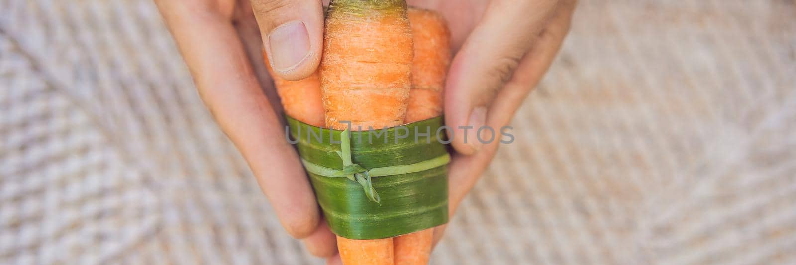 BANNER, LONG FORMAT Eco-friendly product packaging concept. Carrot wrapped in a banana leaf, as an alternative to a plastic bag. Zero waste concept. Alternative packaging.