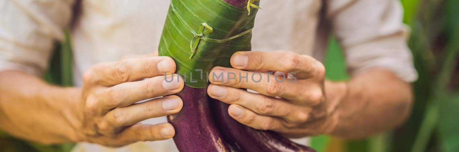 BANNER, LONG FORMAT Eco-friendly product packaging concept. Eggplant wrapped in a banana leaf, as an alternative to a plastic bag. Zero waste concept. Alternative packaging.