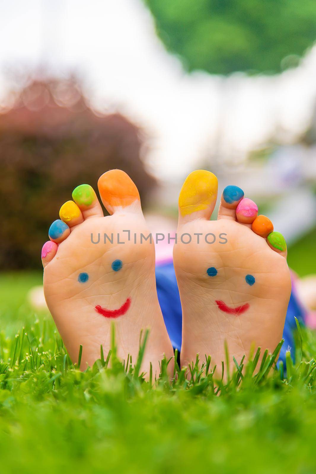 Feet of a child on the grass with a painted smile. Selection focus. Kid.