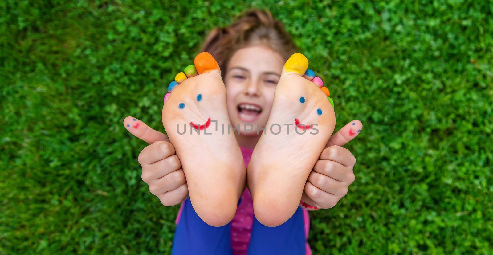 Feet of a child on the grass with a painted smile. Selection focus. Kid.