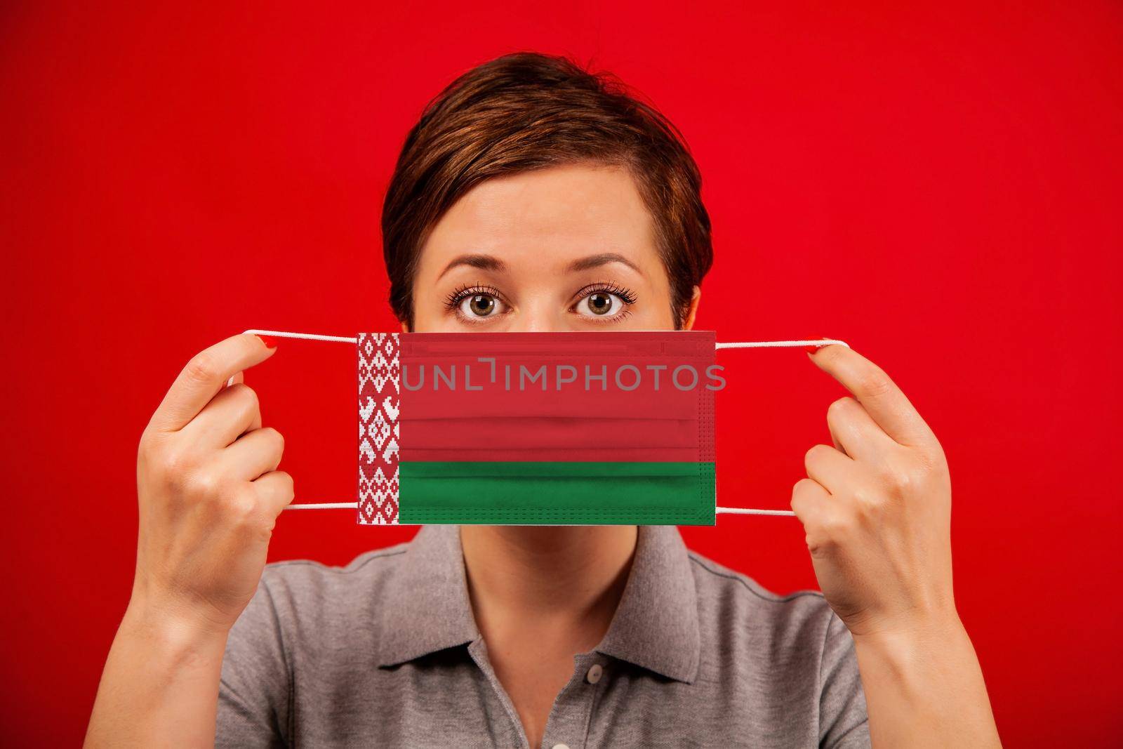 Coronavirus COVID-19 in Belarus. Woman in medical protective mask with the image of the flag of Belarus. The concept of preventing the spread of the epidemic and treating coronavirus.