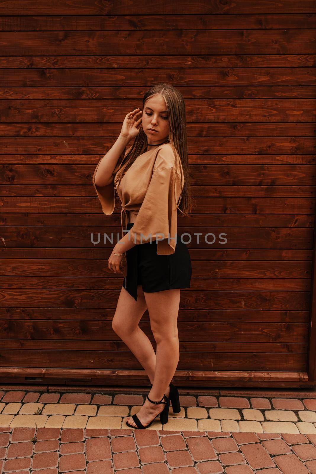 Ukrainian young woman in a mini skirt. Fashion summer 2021 style glamorous. Brown wooden striped background.