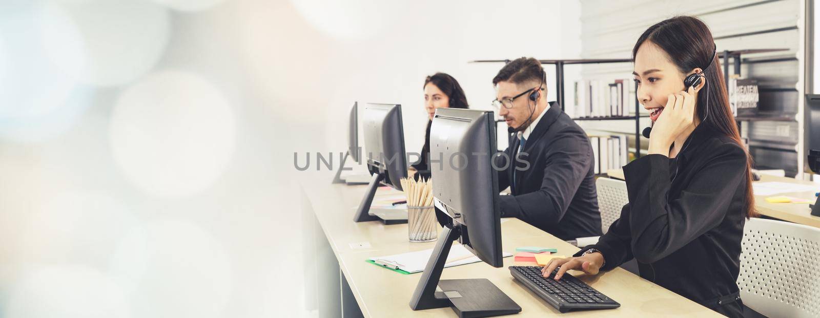 Business people wearing headset working in office to support remote customer or colleague. Call center, telemarketing, customer support agent provide service in broaden view .