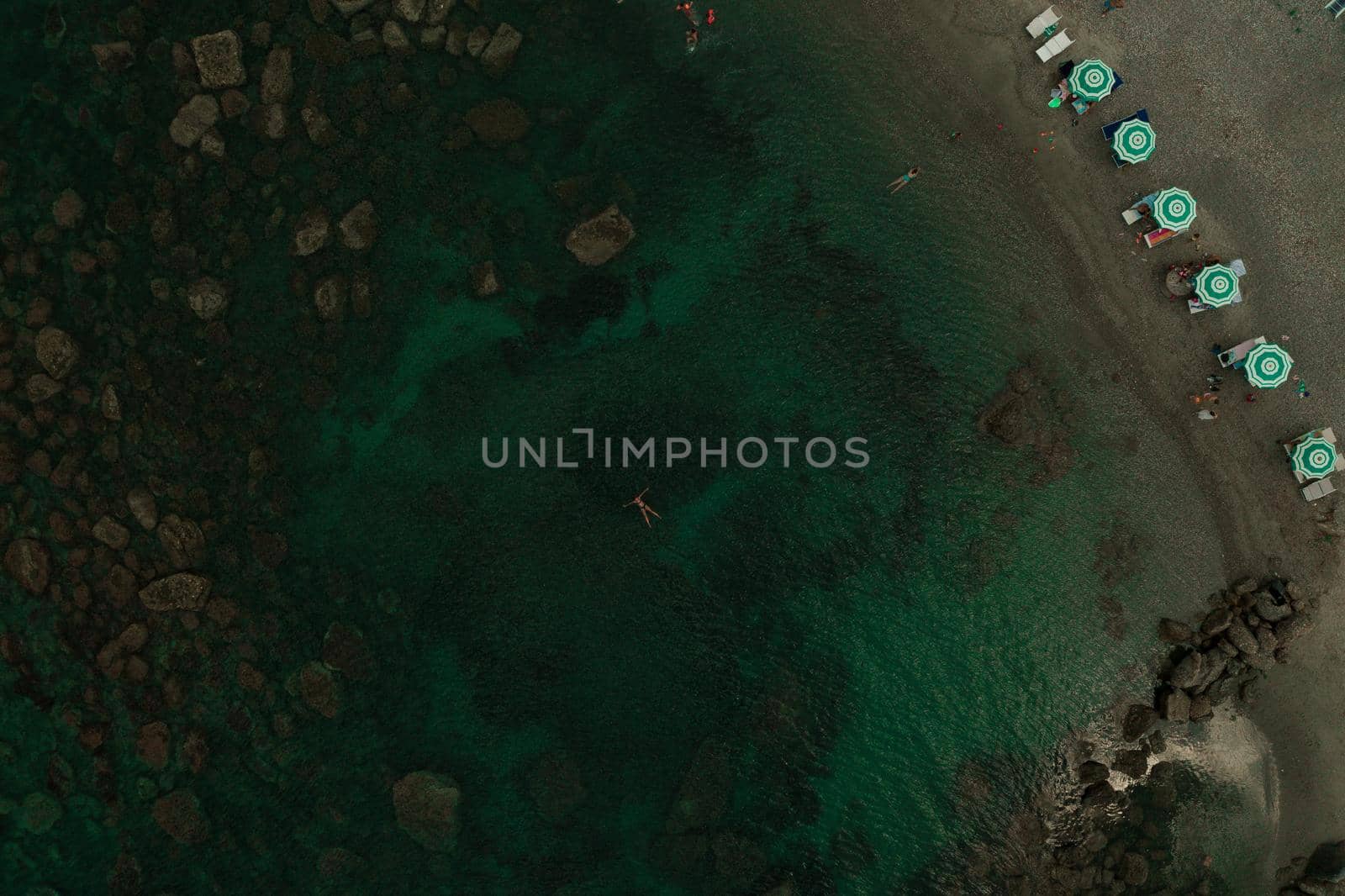 Aerial top nature view above green turquoise Adriatic sea in Albania. Beautiful young woman swimming alone in middle ocean water. girl in swimsuit bikini lying. wide panoramic view marine. summer