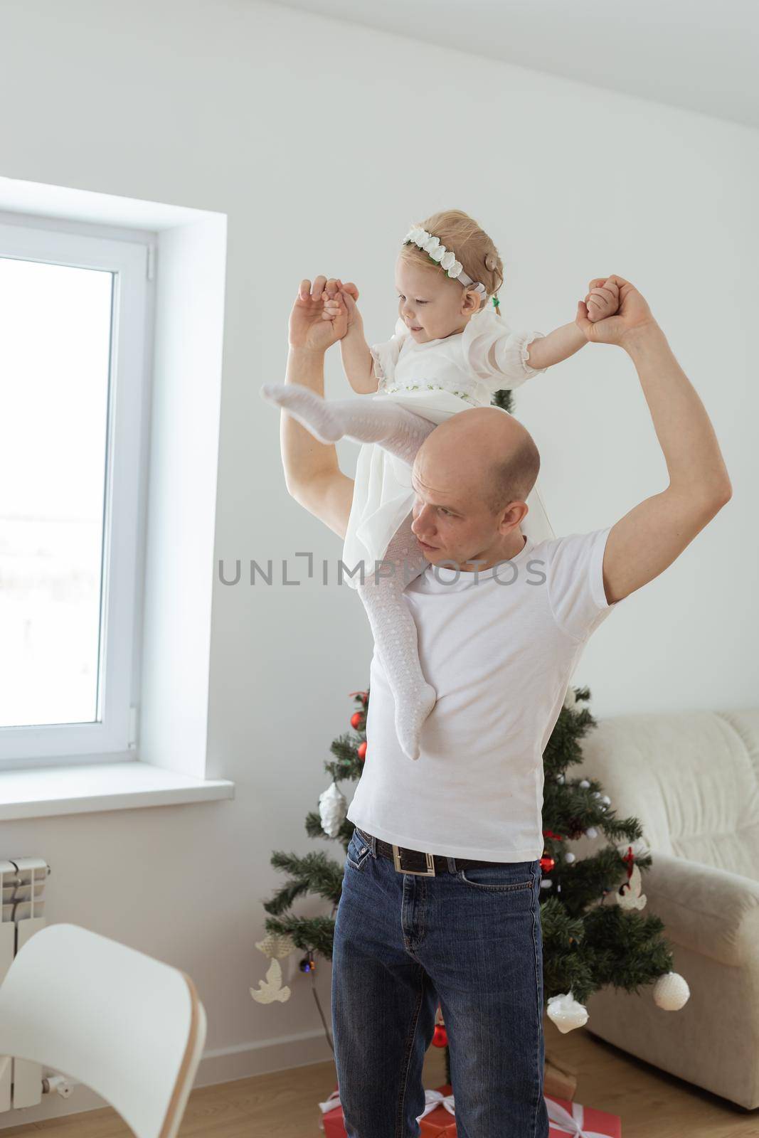 Baby child with hearing aid and cochlear implant having fun with father on christmas tree background. Deaf , diversity and health concept by Satura86