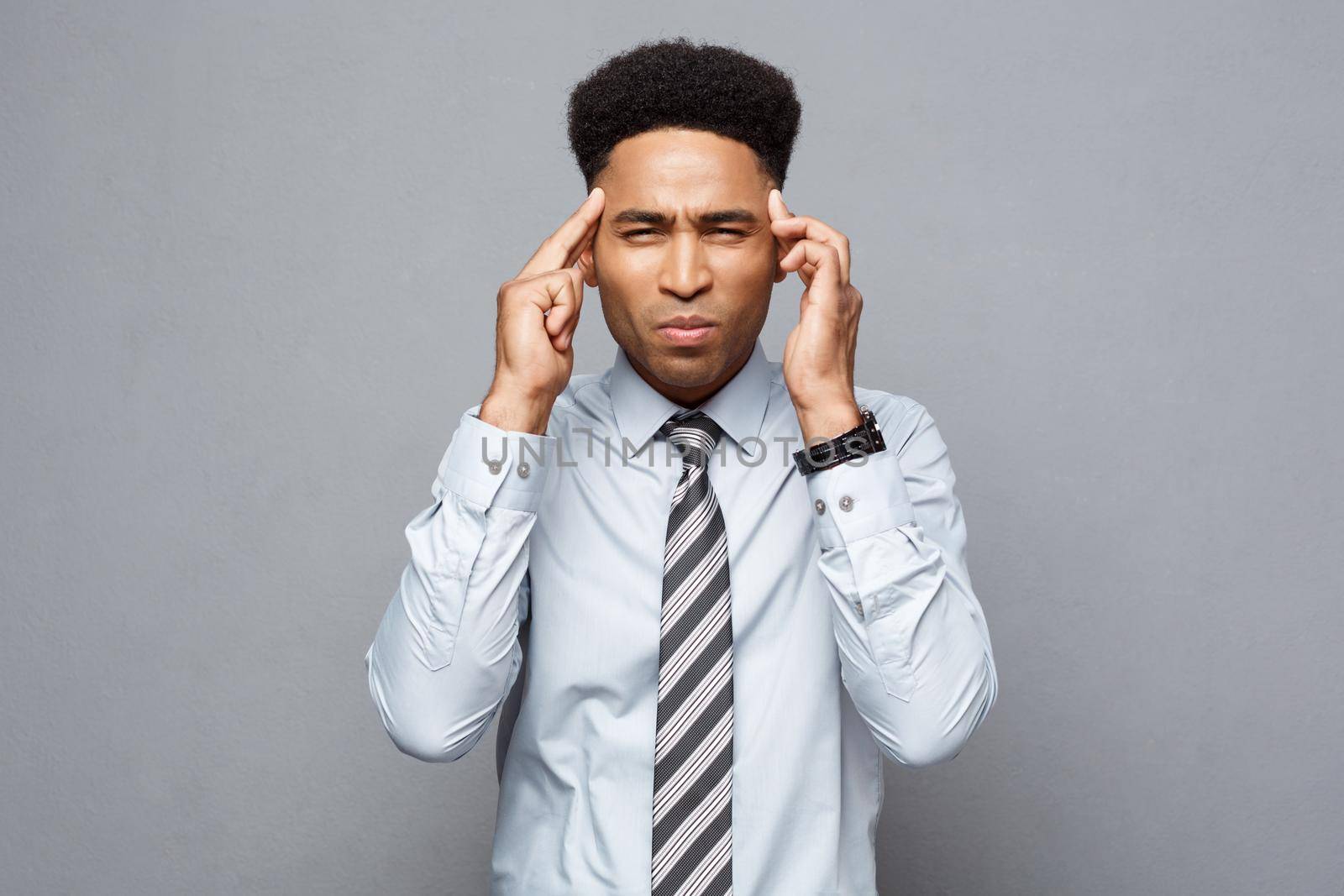 Business concept - portrait of frustrated stressed African American business man on grey background