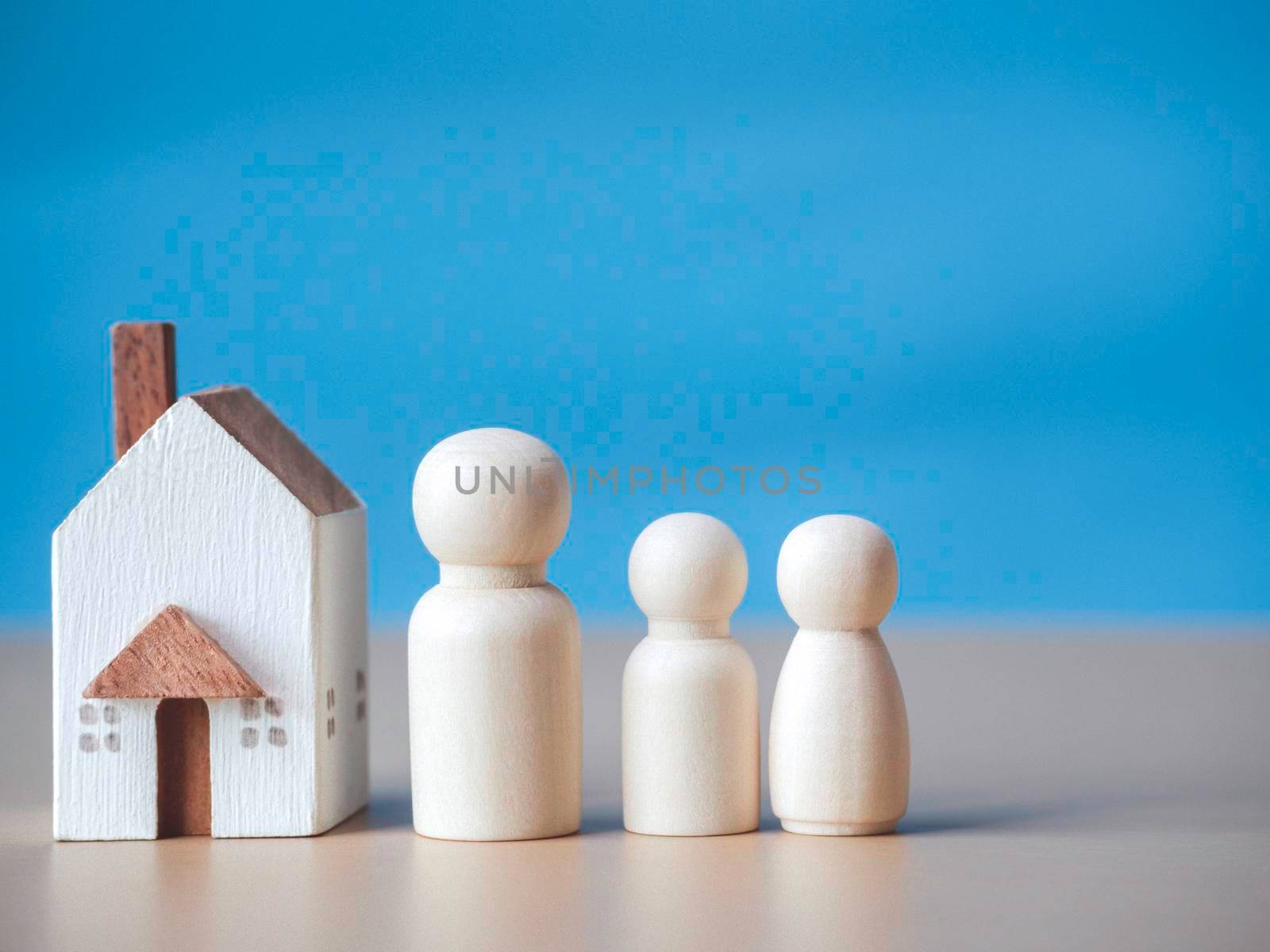 Three wooden figures people standing nearby of tiny wooden house. Concept for family, loan, property ladder, financial, mortgage, real estate investment, taxes and bonus. by Chakreeyarut