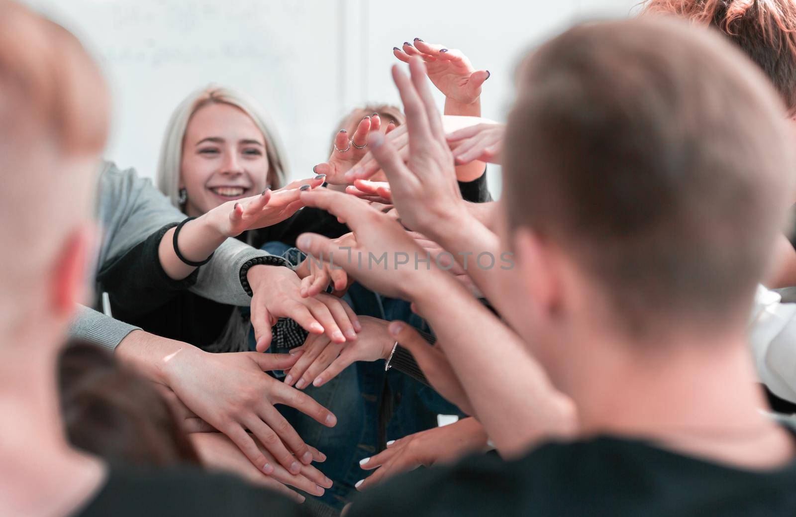 close up. a group of young people joining their palms in a pile . the concept of unity