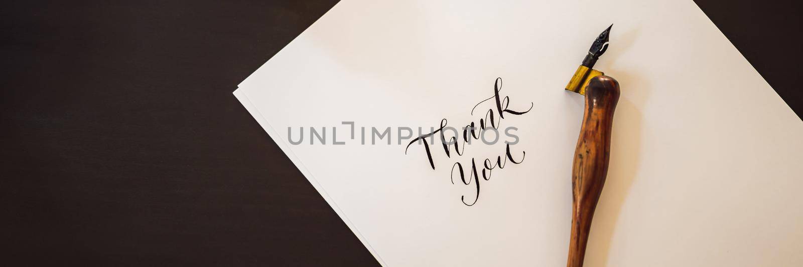 BANNER, LONG FORMAT Thank you. Calligrapher Young Woman writes phrase on white paper. Inscribing ornamental decorated letters. Calligraphy, graphic design, lettering, handwriting, creation concept.